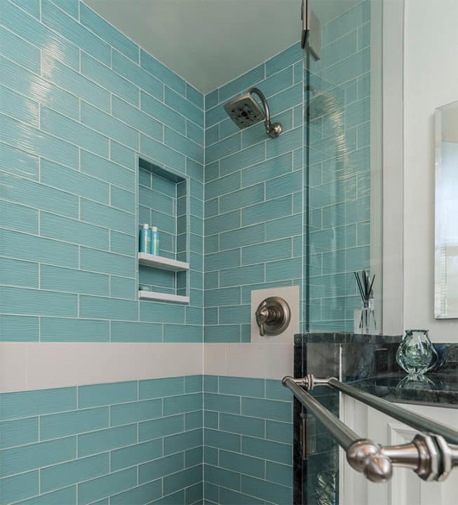 single shower head in teal glass tile shower